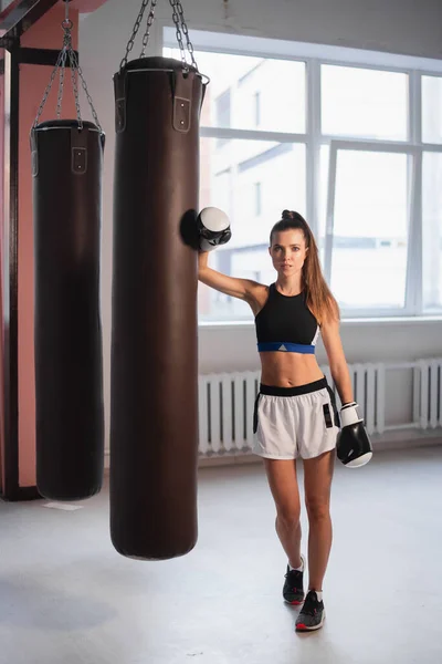 Hermosa mujer kickboxing entrenamiento con bolsa en el gimnasio. — Foto de Stock