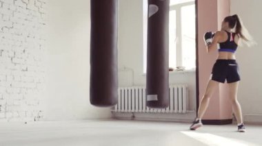 Kentsel endüstriyel spor salonunda boks yapan bayan sporcu.