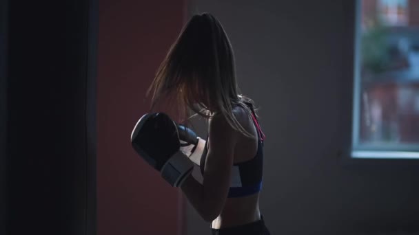 Zpomalený pohyb kickboxer dívka se připravuje na soutěže v boxerské hale, nacvičování techniky údery na boxovací pytel — Stock video