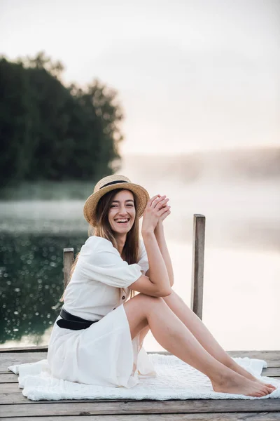 白いドレスと帽子の幸せな白人女性の肖像屋外に座って笑顔. — ストック写真