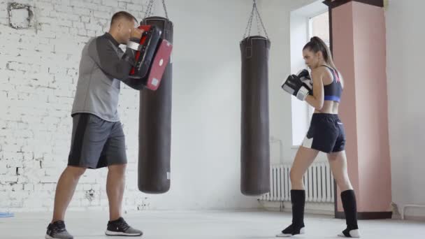 Linda chica aprende técnicas de kickboxing en el gimnasio con un entrenador experimentado — Vídeos de Stock