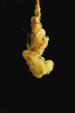 Temiz su ve siyah arkaplanda sarı mürekkep damlaları. arkaplan veya renk referansı için soyut resim.