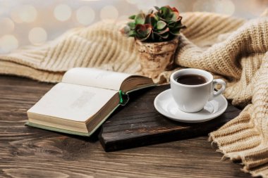 Coffee in bed, romantic morning. Open book and a cup of coffee on a wooden table. Home cozy interior, lifestyle. Selective focus