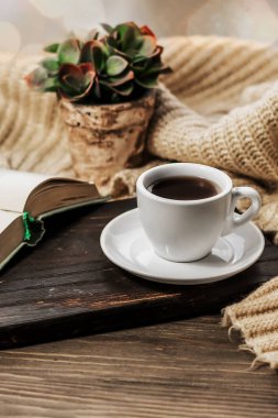 Coffee in bed, romantic morning. Open book and a cup of coffee on a wooden table. Home cozy interior, lifestyle. Selective focus