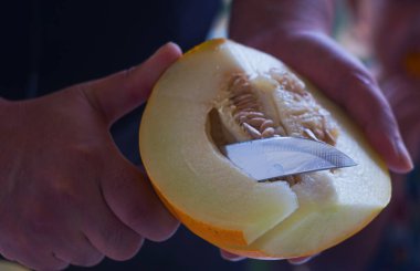                         A man is slicing a yellow melon       