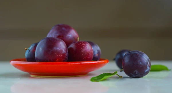 There are plums in the red bowl