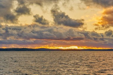 Baltık Denizi 'nde renkli bir günbatımı. Ufukta güneşin batışı ile aydınlanan bulutlar.