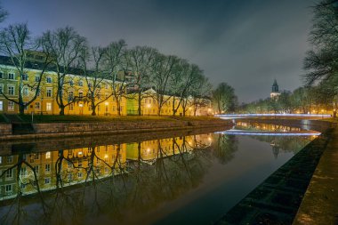 Finlandiya Turku 'daki Aura Nehri' nin gece panoramik manzarası. Arkaplanda bir katedral ve köprü kulesi vardır.