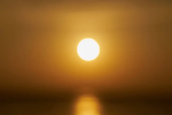 A blurry sun rising over the sea at dawn. — Stok fotoğraf