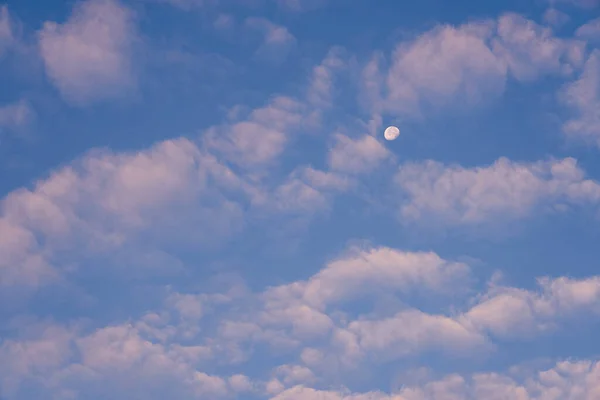 La luna en el cielo azul entre las nubes es como un fondo. — Foto de Stock