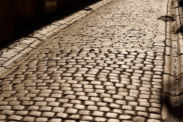 The road is made of granite tiles in the rays of the sun