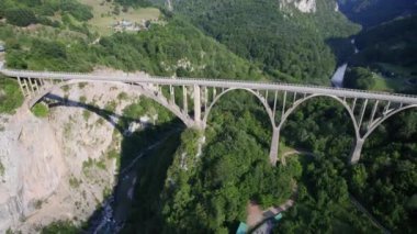 Bir dağ zirvesinin altındaki buzul gölü havadan çekilen yeşil kozalaklı ağaçlarla çevrilidir. Suyun hemen üstünde ve kıyı boyunca gölün büyüklüğünü ve gölün çevresini en az renk düzeltmesi ile gözler önüne serer.