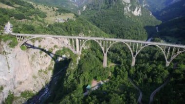Bir dağ zirvesinin altındaki buzul gölü havadan çekilen yeşil kozalaklı ağaçlarla çevrilidir. Suyun hemen üstünde ve kıyı boyunca gölün büyüklüğünü ve gölün çevresini en az renk düzeltmesi ile gözler önüne serer.