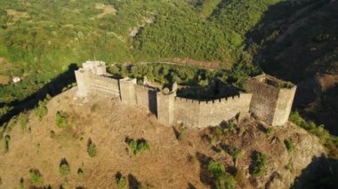 Gün doğumunda tepedeki bir ortaçağ kalesinde yüksek açılı dairesel bir dron atışı.