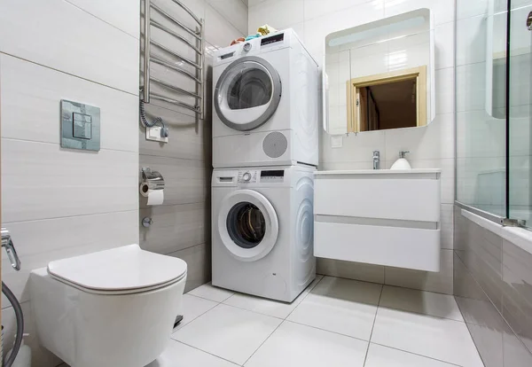 Çamaşır makinesi ve kurutma makinesi olan modern bir banyo..