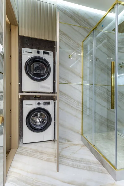 Modernes Badezimmer mit Marmorfliesen und Waschmaschine und Wäschetrockner im Holzschrank — Stockfoto