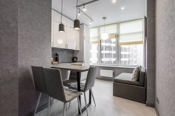 Clean kitchen in a small cozy contemporary studio apartment. Table and chairs in the foreground. Built in household appliance — Stock Photo, Image