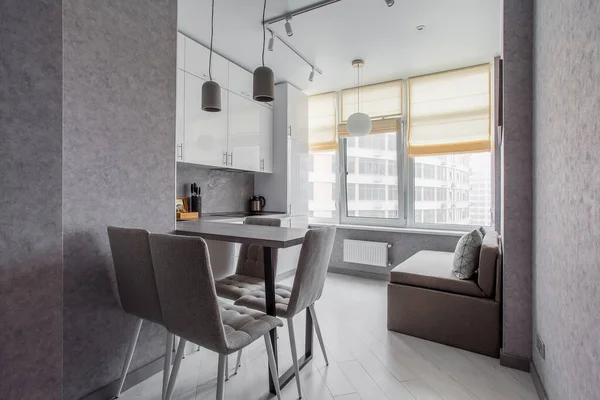 Clean kitchen in a small cozy contemporary studio apartment. Table and chairs in the foreground. Built in household appliance — Stock Photo, Image