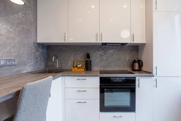 Clean kitchen in a small cozy contemporary studio apartment. Table and chairs in the foreground. Built in household appliance — Stock Photo, Image