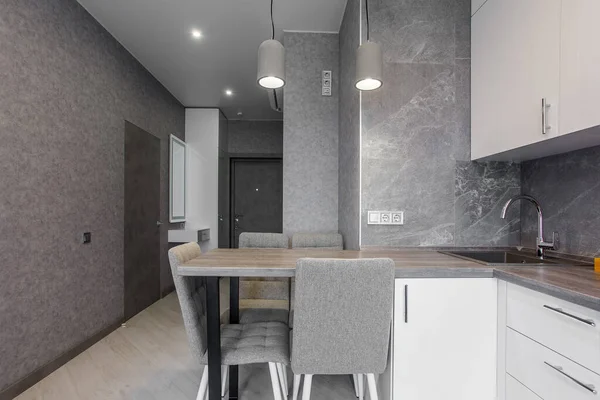 Saubere Küche in einem kleinen gemütlichen modernen Studio-Appartement. Tisch und Stühle im Vordergrund. Eingebautes Haushaltsgerät — Stockfoto