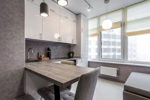 Saubere Küche in einem kleinen gemütlichen modernen Studio-Appartement. Tisch und Stühle im Vordergrund. Eingebautes Haushaltsgerät — Stockfoto