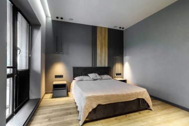 Koyu ve gri stili modern ve tavan arası yatak odası. Koyu yatak başlığı ve cam pencereli ahşap zemin..