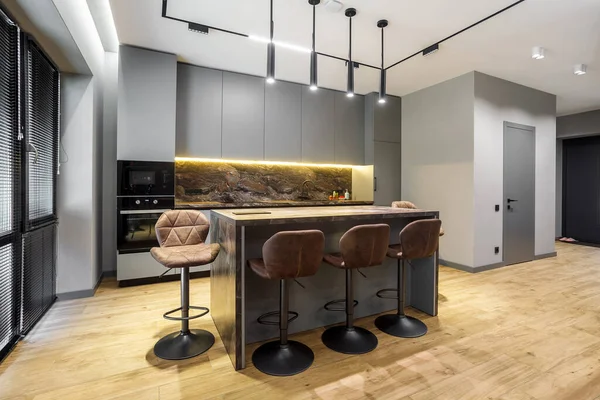 Modern luxury apartment with a free layout in a loft style in gray and dark colors. Stylish kitchen area with an island marble countertop