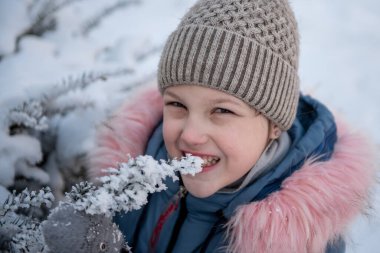 Mutlu gülümseyen çocuk, kışın dışarı çıkıp karla oynayan kız. Karla kaplı bir ağacın yanında bir kızın portresi