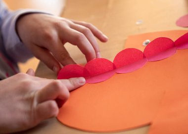 Çocuk renkli kağıtlardan bir uygulama yapıyor. Yaratıcı çocuk oyunu zekası. Çocuk gelişimi. El sanatlarının sinagog eğitimi. Kağıt ile ev eğitimi oyunu. Erken gelişme.