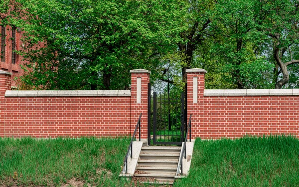 Brick fence and entrance to the yard. Red brick fence. Entrance. Gate in a private house. Metal gate guarding the entrance to the house