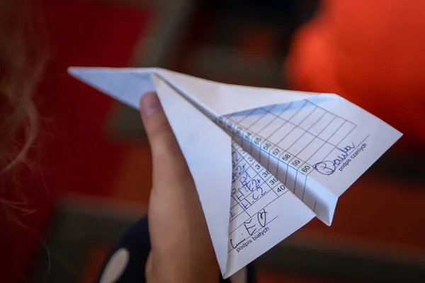 A paper airplane is in the hands of child. The record of chess party builds in an airplane. Origami