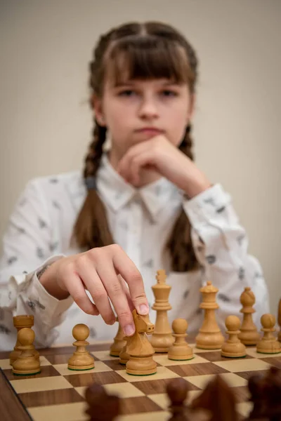 The girl plays chess. Figures on a chessboard. Chess game, close-up, portrait