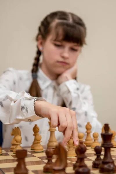 The girl plays chess. Figures on a chessboard. Chess game, close-up, portrait