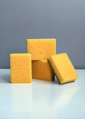 Sarı mutfak süngerleri beyaz bir masada. Bulaşık ve diğer ev ihtiyaçları için süngerler. Sarı sünger tasarımı, yakın plan temizlik süngeri. Yüksek kalite fotoğraf