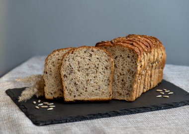 Tohumlu çavdar ekmeği açık bir masada, karanlık bir tahtanın üzerinde yatıyor. Ev pastanem. Organik tam tahıllı ekmek. Bio Dinkel Brot. Sağlıklı ekmek. Karbonhidratlar. Sağlıklı beslenme. Sağlıklı kahvaltı. kahverengi ekmek.
