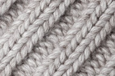 Hafif örülmüş kumaş arka plan - gri, bej, beyaz. Kumaşın doğal bir dokusu var. Yünden örgü deseni. Kış giysileri, eşarp, yakın çekim. Duvar kağıdı, makro