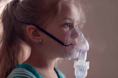 Şirin küçük kız hasta. Akciğer hastalığı, covid-19. Çocuk solunum yolundaki nebulizatörle solunum prosedürünü uyguluyor. Çocuğa öksürük tedavisi uyguluyorum. Sıkıştırma spreyi. Sağlık konsepti. izole