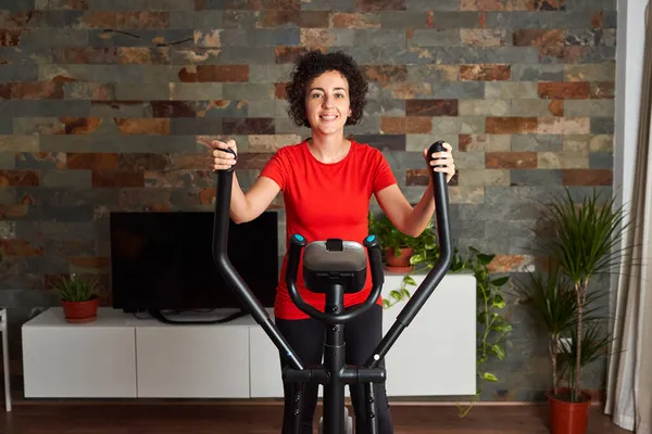 Woman training at home using elliptical cross trainer