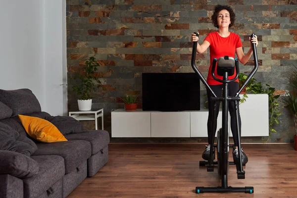 Woman training at home using elliptical cross trainer — Stock Photo, Image