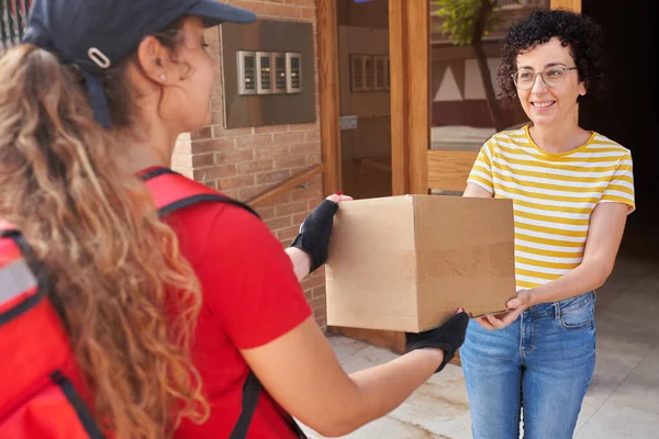 Una repartidora entrega un paquete a un cliente en la calle — Foto de Stock