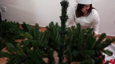 Bir kadın yerde yapay bir Noel ağacı kuruyor.