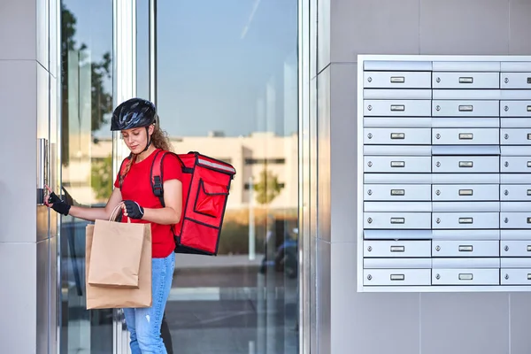 Una repartidora de ciclistas tocando la campana del intercomunicador — Foto de Stock