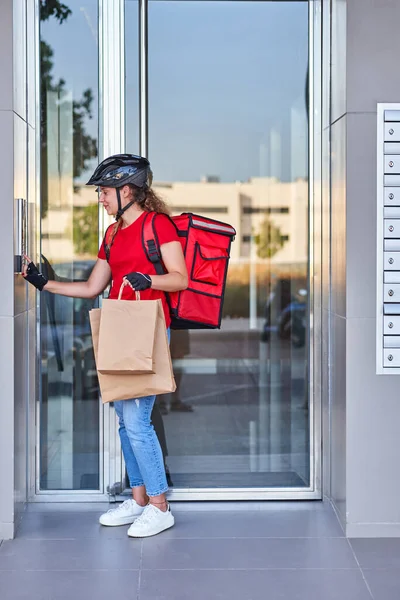 Una repartidora de ciclistas tocando la campana del intercomunicador — Foto de Stock