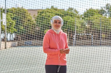 Kulaklıklı genç Müslüman bir sporcunun portresi.