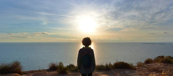 Güneş denizin üzerinden doğarken, bir kadının arkadan panoramik görüntüsü. — Stok fotoğraf