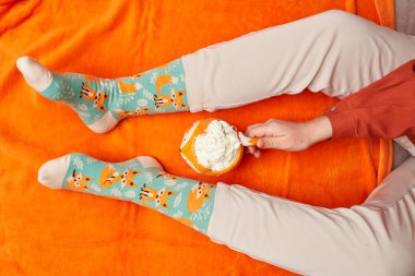 Turuncu battaniyeli kanepede dinlenen kadın bacakları.