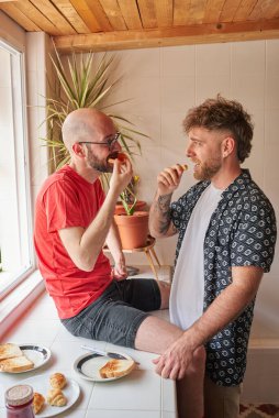 Eşcinsel çift mutfak tezgahında kahvaltı yapıyor.