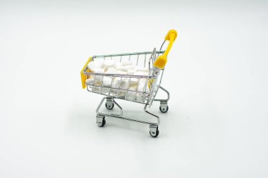 Beyaz arka planda haplar ve tabletlerle dolu mini bir alışveriş arabası. Beyaza izole edilmiş haplarla dolu bir alışveriş arabası. Alışveriş arabası şakası..