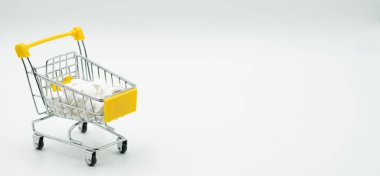 Beyaz arka planda haplar ve tabletlerle dolu mini bir alışveriş arabası. Beyaza izole edilmiş haplarla dolu bir alışveriş arabası. Alışveriş arabası şakası..