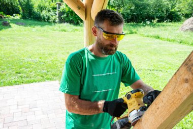 İşçi kendi çalışma yerinde köşeli öğütme makinesinin ahşabını öğütüyor. Çalıştığımız odun kadar sağlam.